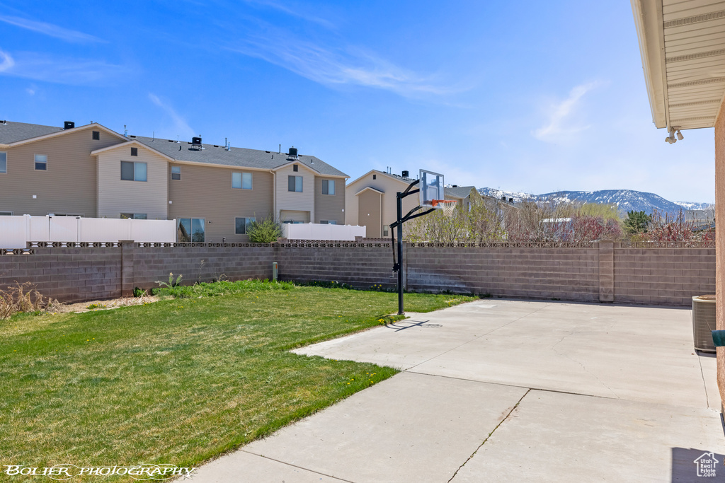 View of yard featuring a residential view, basketball court, cooling unit, and a mountain view