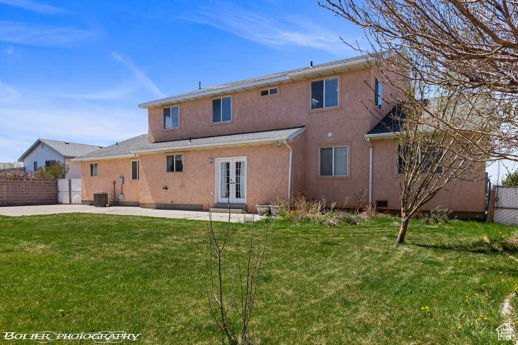 Back of property featuring french doors, stucco siding, central AC unit, and a patio area
