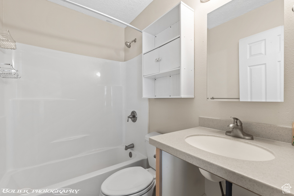 Bathroom with toilet, bathing tub / shower combination, vanity, and a textured ceiling