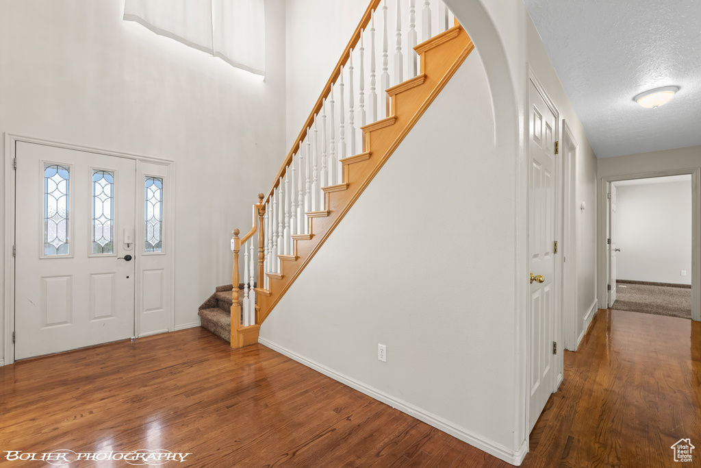 Foyer with stairway, wood finished floors, baseboards, and arched walkways
