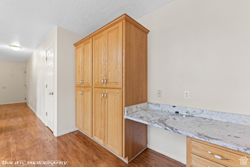 Corridor featuring a desk, light wood finished floors, and baseboards