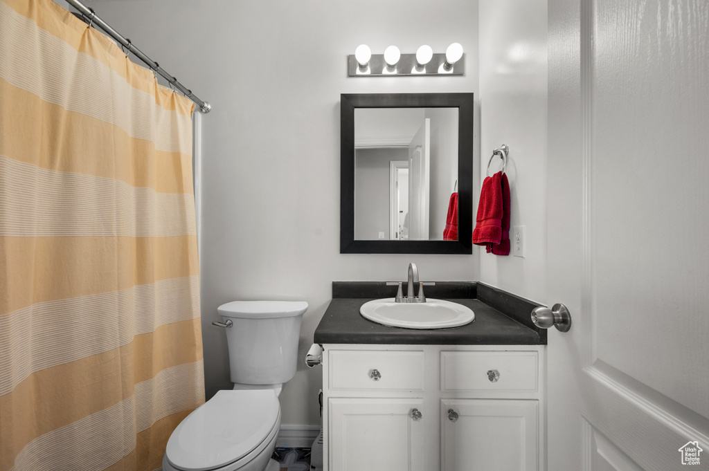 Bathroom with toilet, vanity, and a shower with shower curtain