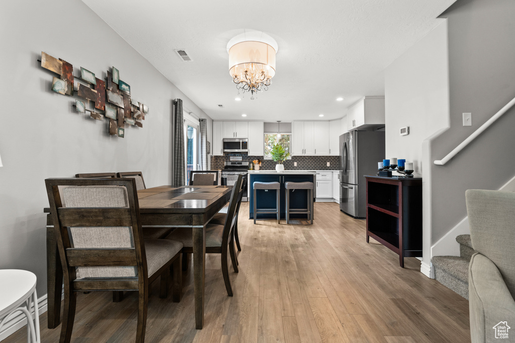 Dining area featuring a chandelier, stairs, light wood-style floors, recessed lighting, and baseboards