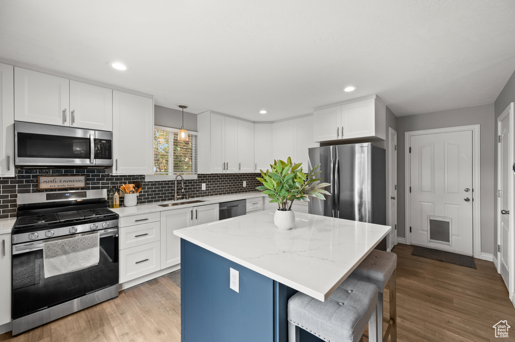 Kitchen featuring stainless steel appliances, a sink, backsplash, white cabinets, and recessed lighting