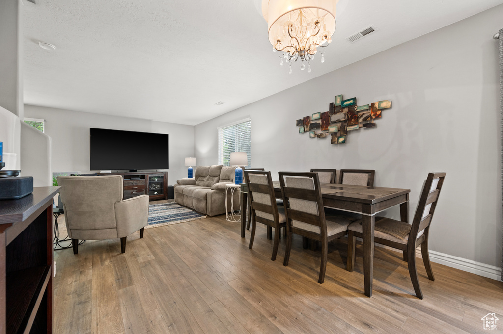 Dining room with light wood-style floors and a chandelier