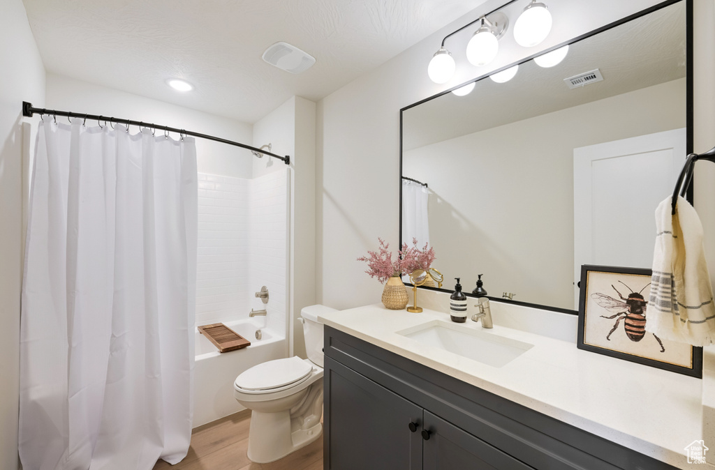 Full bath featuring wood finished floors, toilet, vanity, and shower / bath combination with curtain
