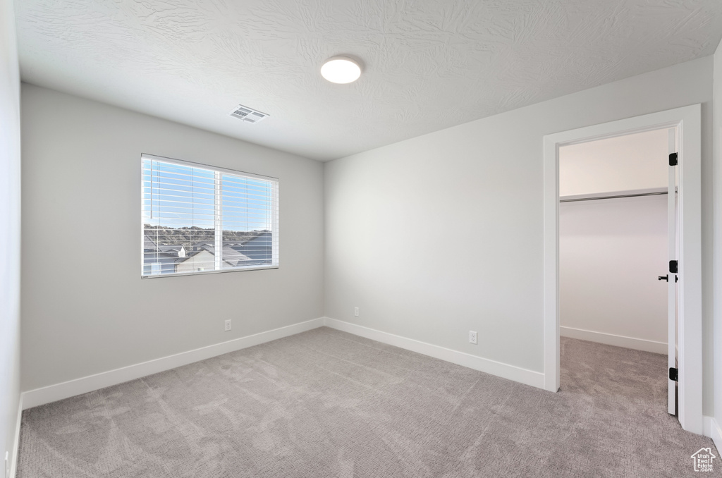Unfurnished bedroom with carpet floors, a walk in closet, baseboards, and a closet