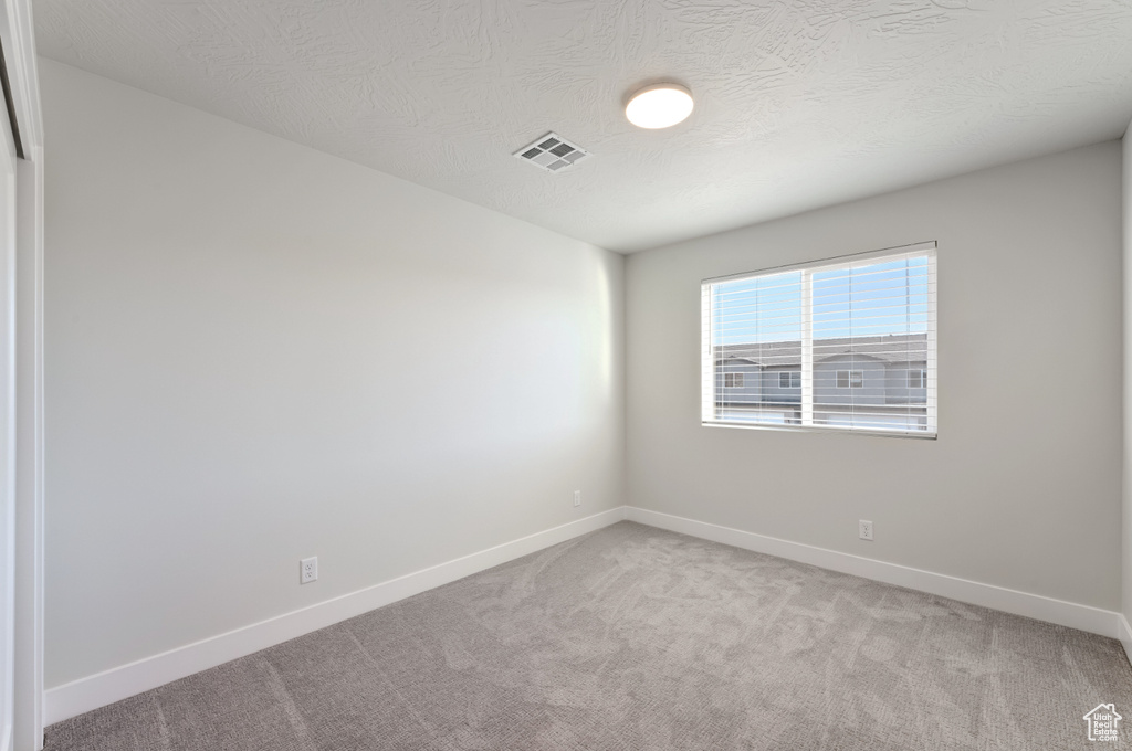 Unfurnished room featuring light carpet and baseboards