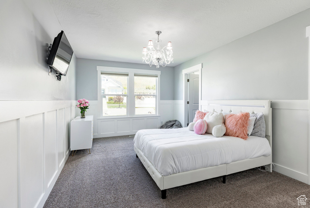 Bedroom with carpet, a chandelier, wainscoting, and a decorative wall