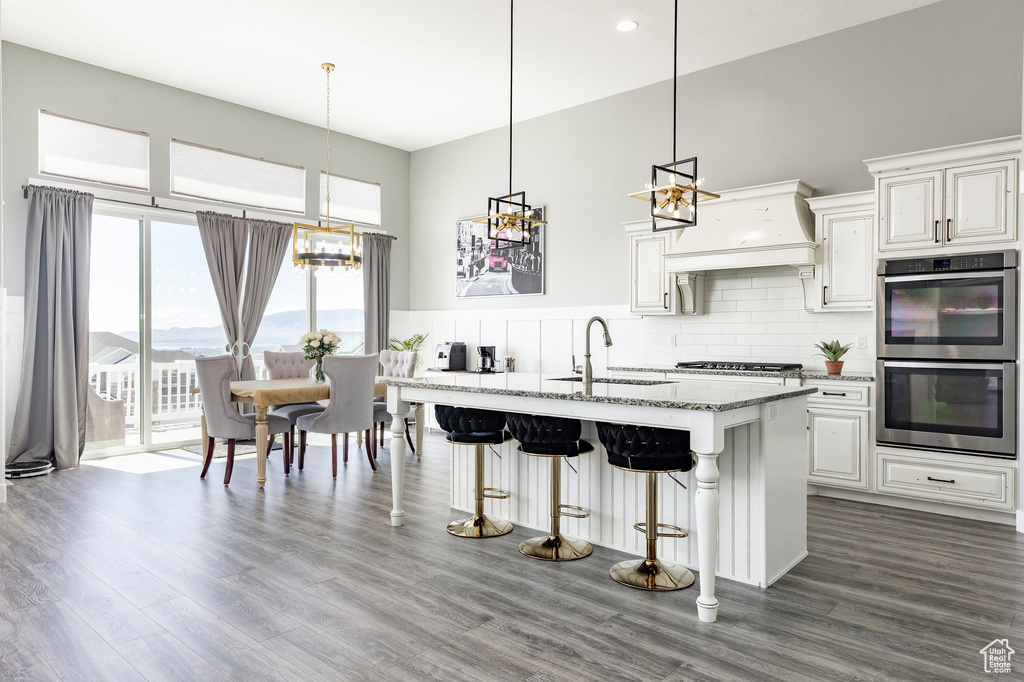 Kitchen featuring a sink, stainless steel appliances, light stone counters, a breakfast bar, and a high ceiling