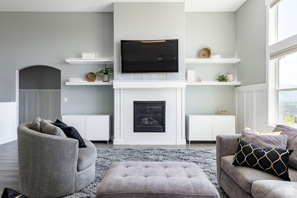 Living area with wood finished floors, a decorative wall, a wainscoted wall, and a glass covered fireplace