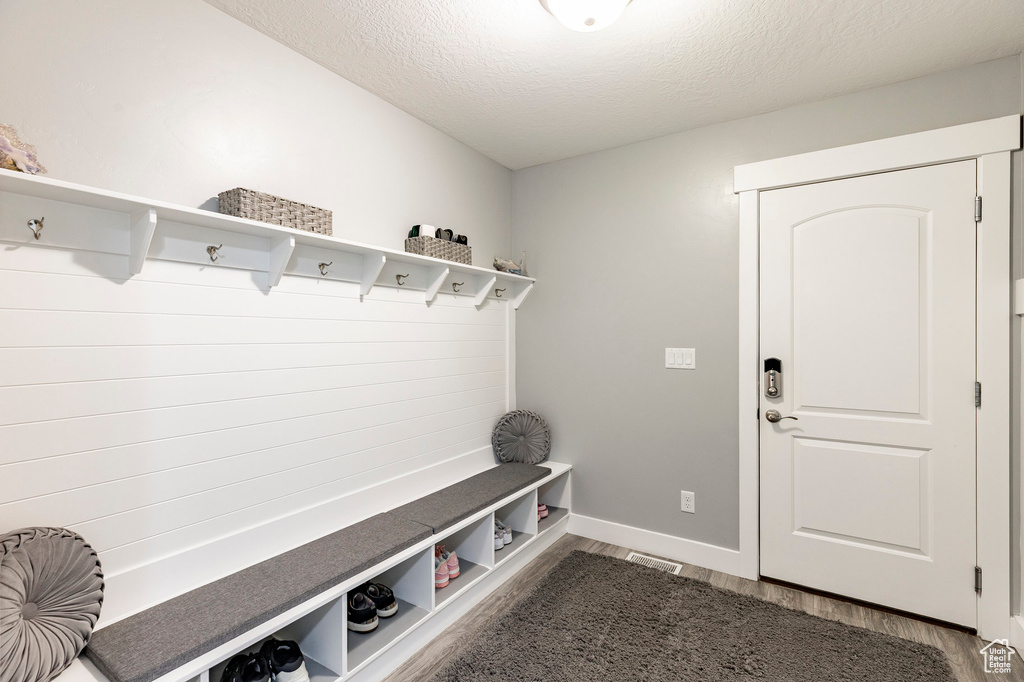 Mudroom with wood finished floors, a textured ceiling, and baseboards