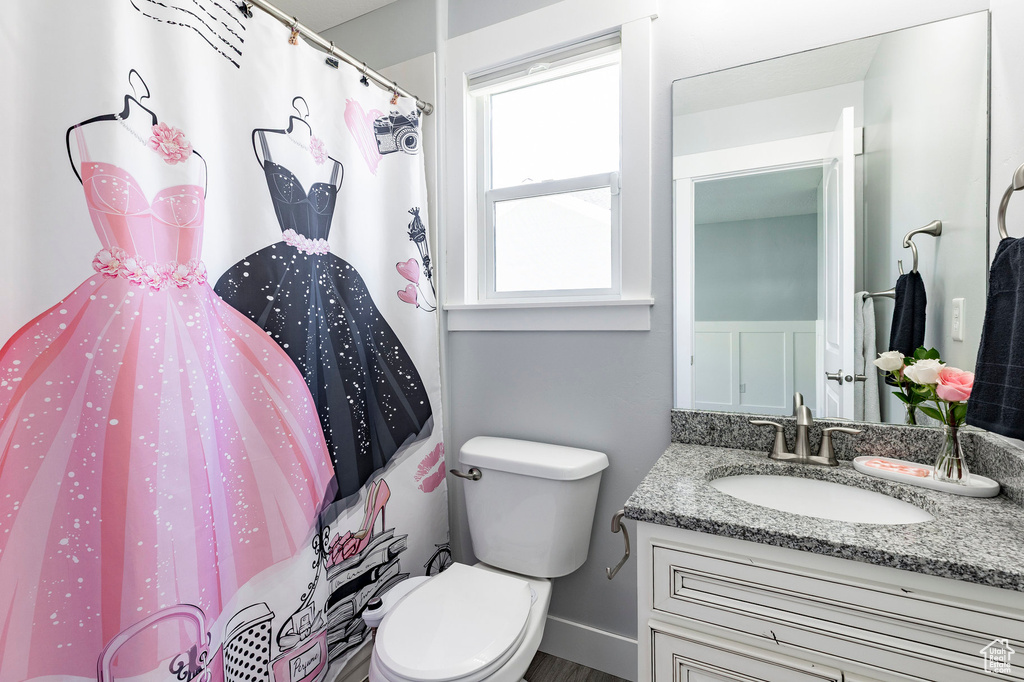 Bathroom with vanity, toilet, and curtained shower