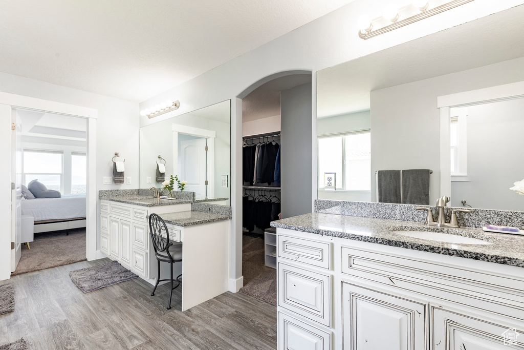 Bathroom with healthy amount of natural light, wood finished floors, two vanities, and ensuite bath