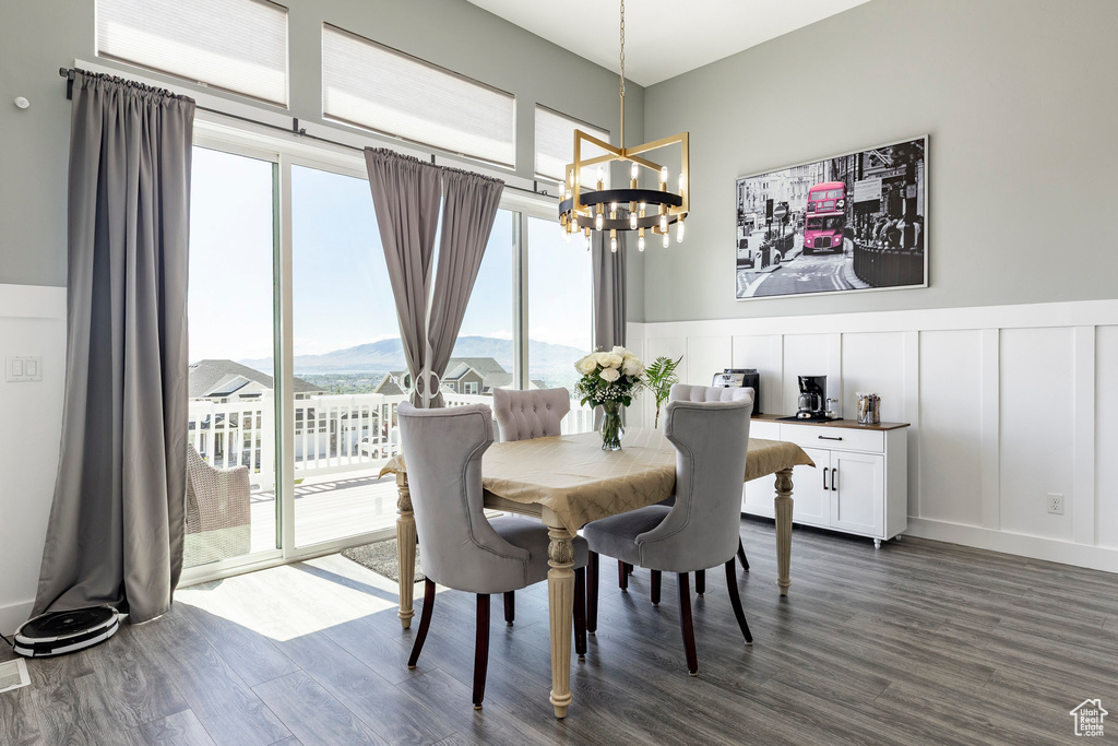 Dining area with a chandelier, dark wood finished floors, a decorative wall, wainscoting, and a mountain view