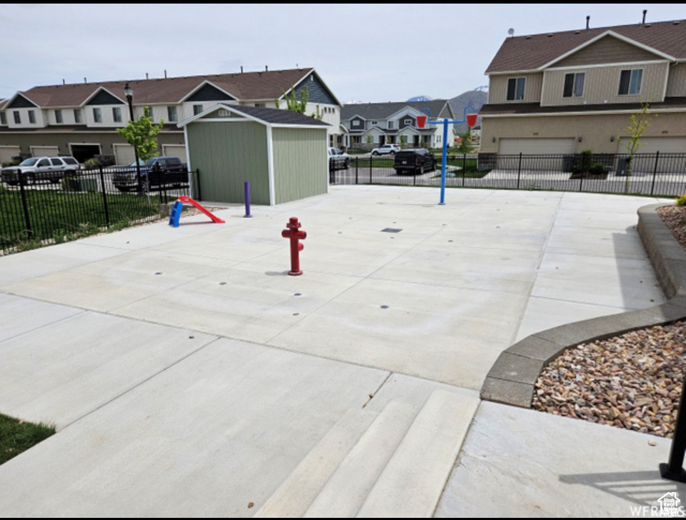 View of community with a residential view, fence, a garage, and concrete driveway