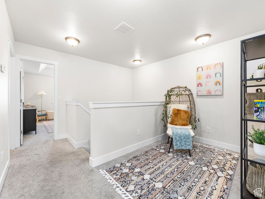 Living area featuring carpet, an upstairs landing, and baseboards