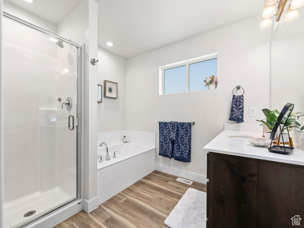 Bathroom featuring a bath, vanity, a stall shower, baseboards, and recessed lighting