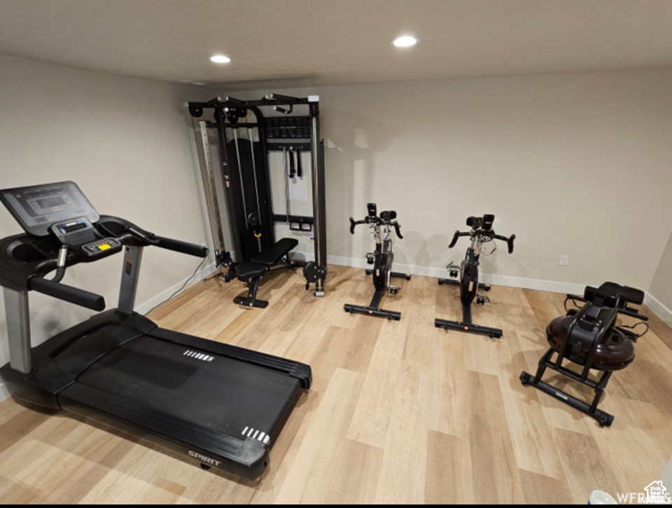 Workout area featuring wood finished floors, baseboards, and recessed lighting