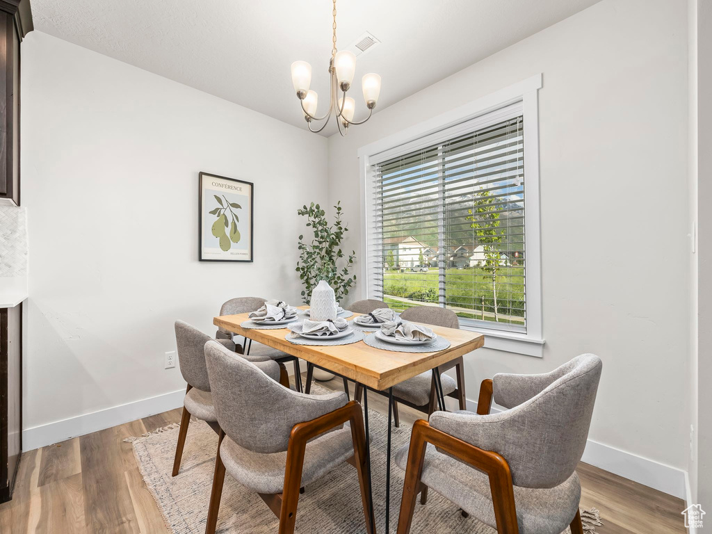 Dining space with a chandelier, baseboards, and light wood-type flooring