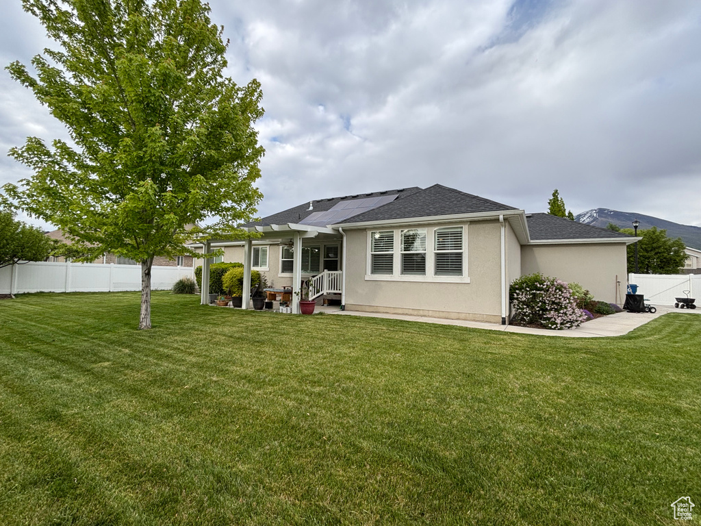 Back of property with stucco siding, a shingled roof, and solar panels