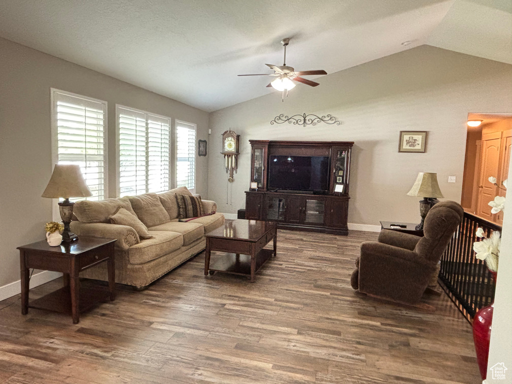 Living area featuring lofted ceiling, a ceiling fan, wood finished floors, and baseboards