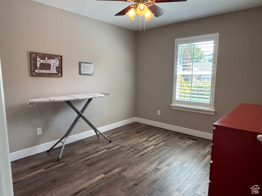 Unfurnished office featuring ceiling fan, dark wood finished floors, and baseboards