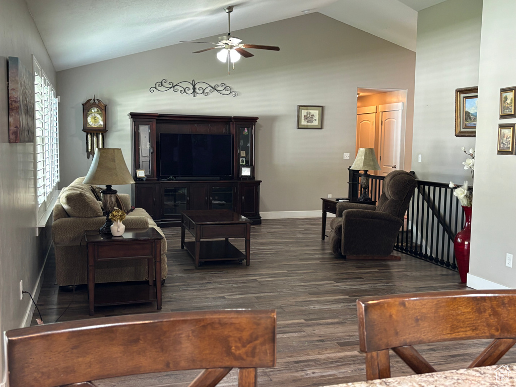 Living area featuring ceiling fan, dark wood-type flooring, baseboards, and high vaulted ceiling