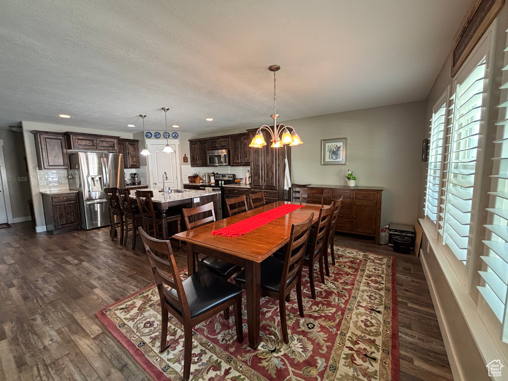 Dining room with a chandelier, dark wood-style floors, recessed lighting, and baseboards