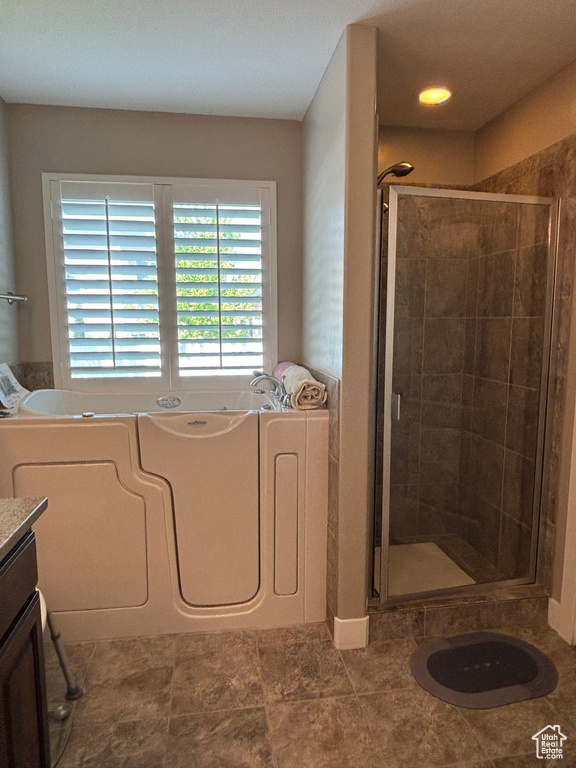 Bathroom featuring a shower stall, a bath, and vanity