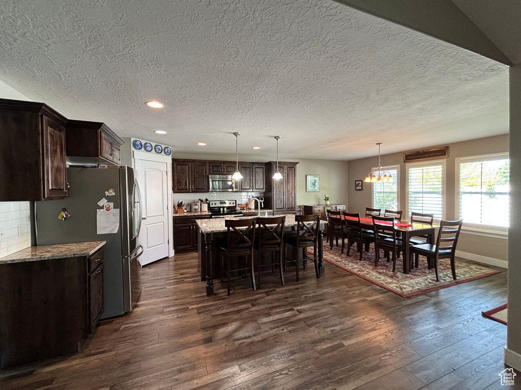 Dining space with dark wood-style flooring, a textured ceiling, recessed lighting, a chandelier, and baseboards