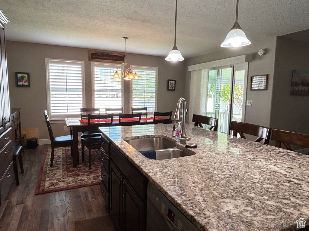 Kitchen featuring a sink, dark wood-style floors, a textured ceiling, baseboards, and light stone counters