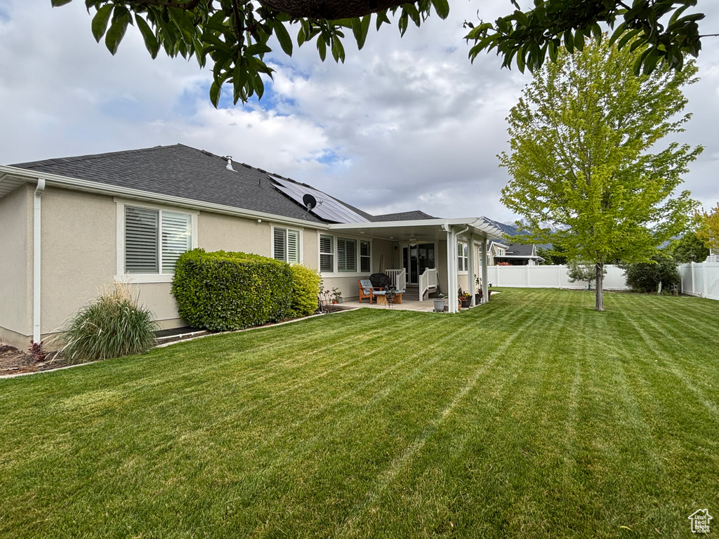 Back of house with a patio area, solar panels, stucco siding, and roof with shingles