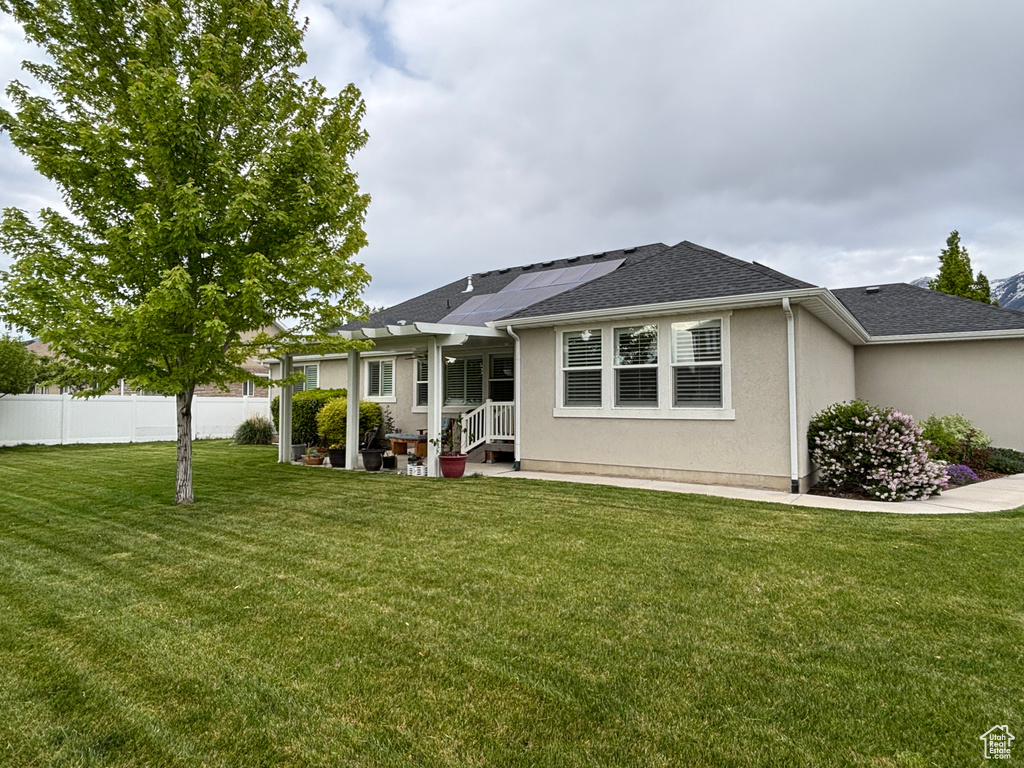 View of front of property featuring roof mounted solar panels, stucco siding, and a shingled roof