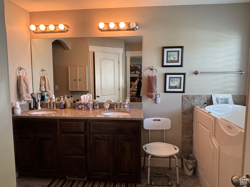Full bathroom with double vanity, a tub to relax in, and tile patterned flooring