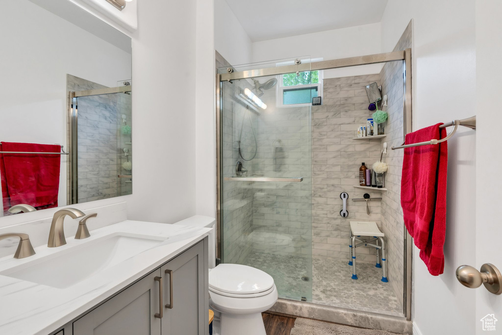 Bathroom with a shower stall, vanity, toilet, and wood finished floors