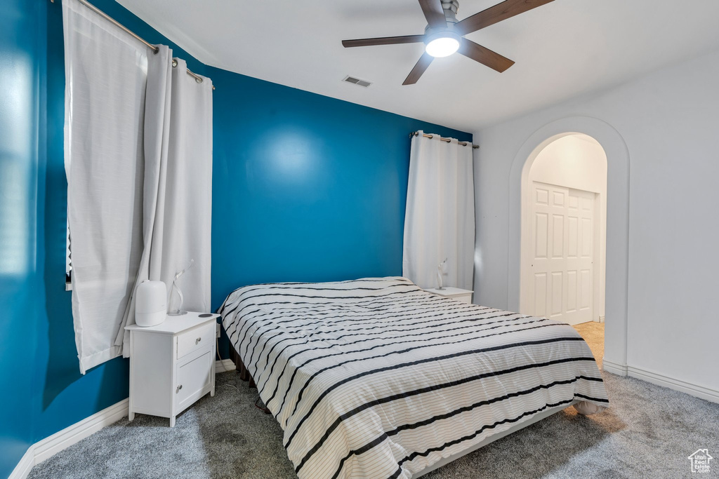 Bedroom featuring carpet, baseboards, arched walkways, and ceiling fan