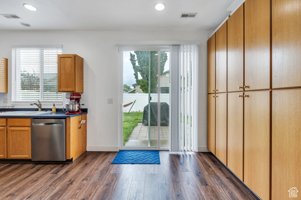 Kitchen featuring stainless steel dishwasher, a sink, dark wood-type flooring, recessed lighting, and dark countertops