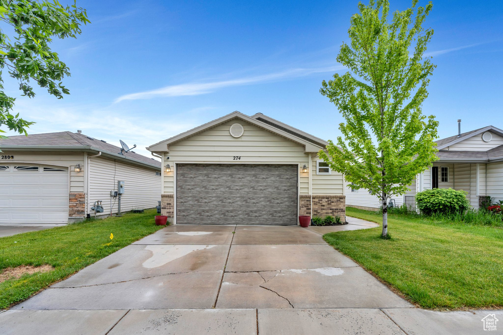 View of front of house with a front lawn, a garage, brick siding, and concrete driveway
