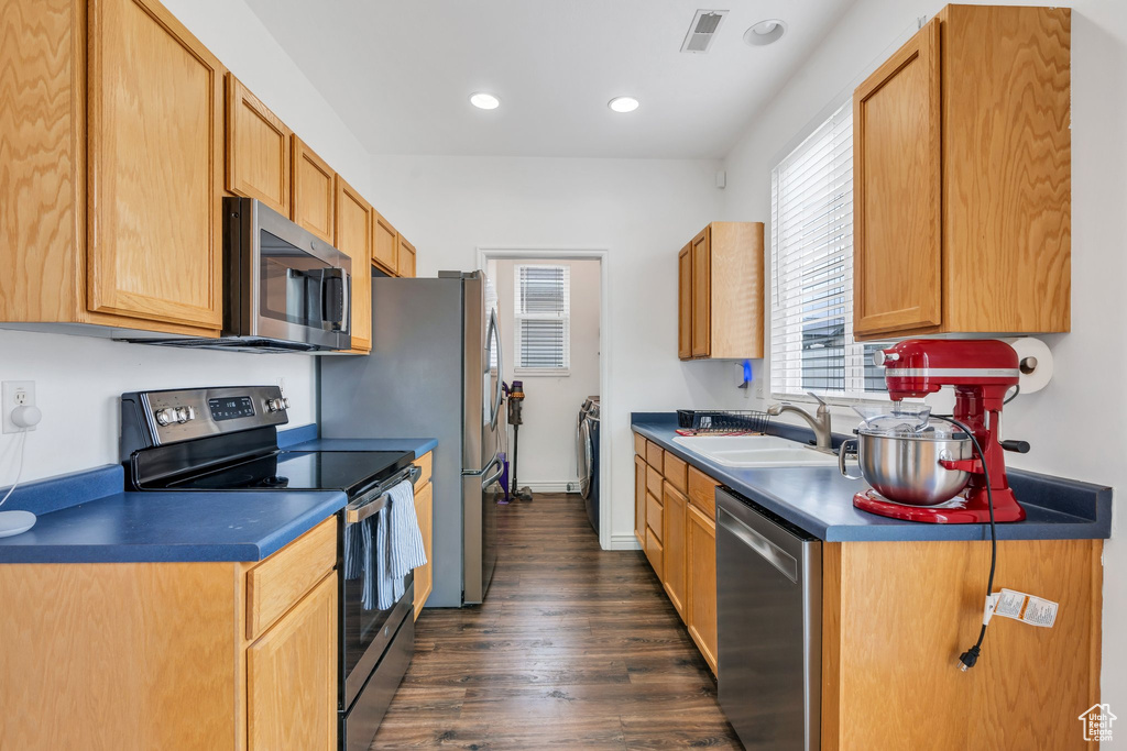 Kitchen with stainless steel appliances, a sink, dark wood-type flooring, dark countertops, and recessed lighting