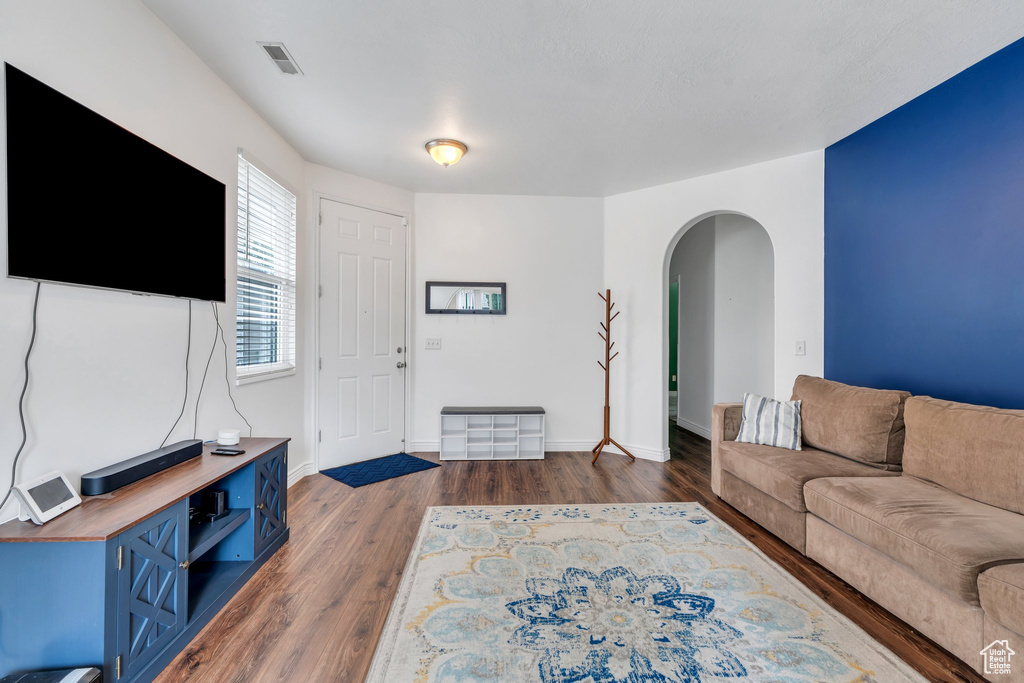 Living room with arched walkways, wood finished floors, and baseboards