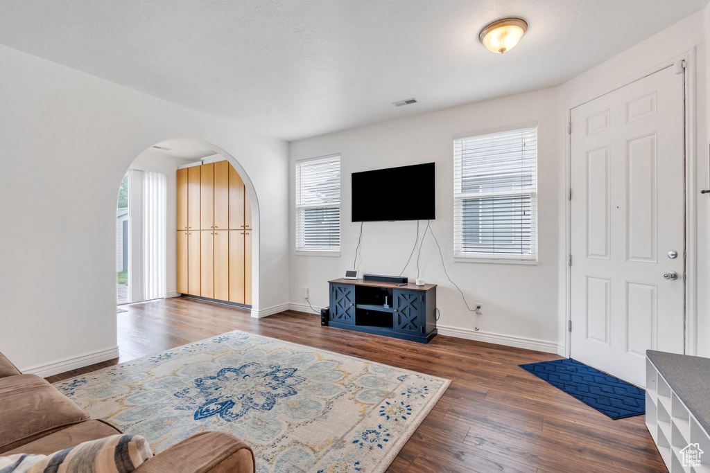 Living room featuring arched walkways, wood finished floors, and baseboards