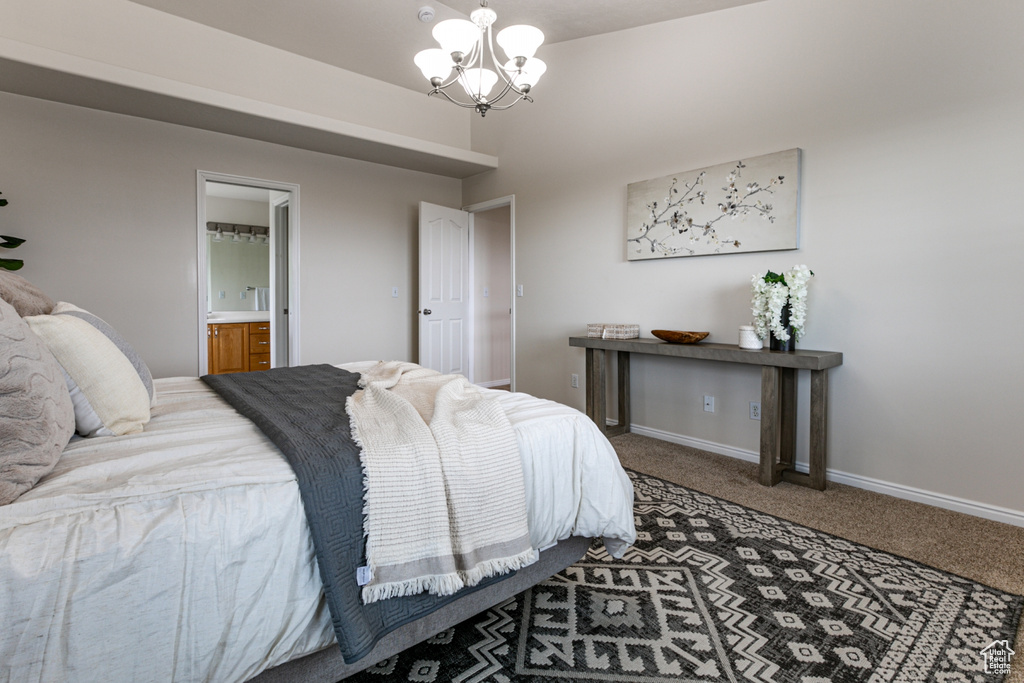 Carpeted bedroom featuring a chandelier, baseboards, and ensuite bath