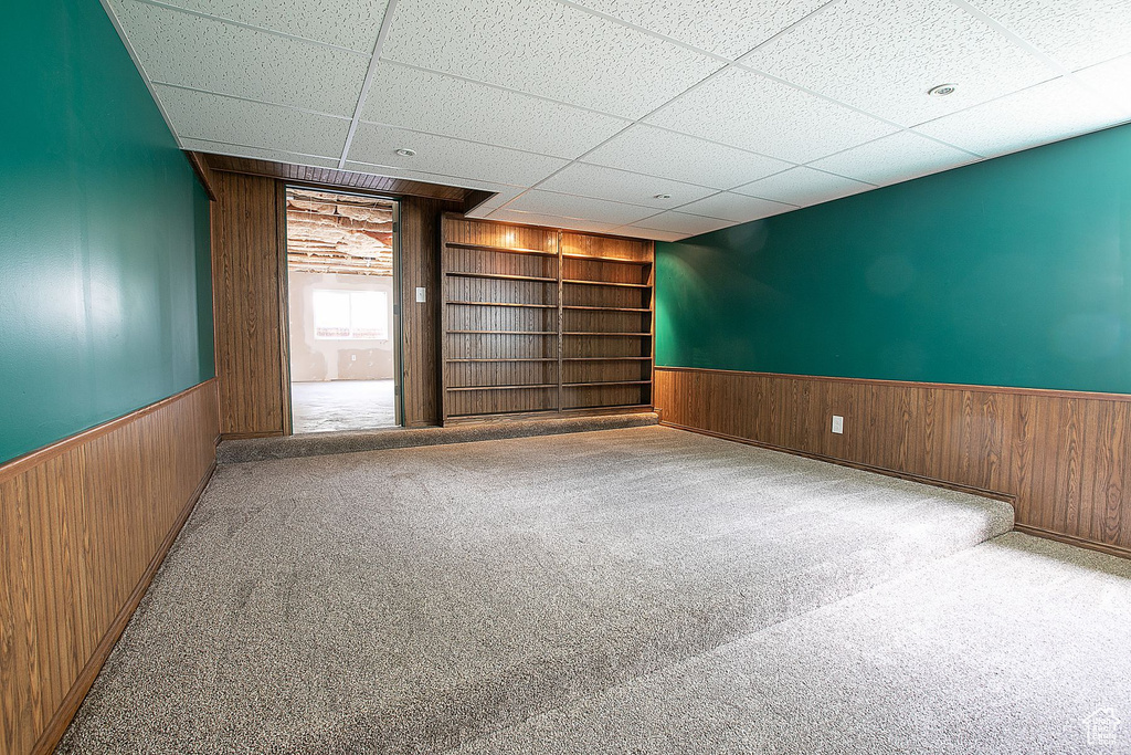 Spare room with wood walls, wainscoting, built in features, carpet, and a paneled ceiling