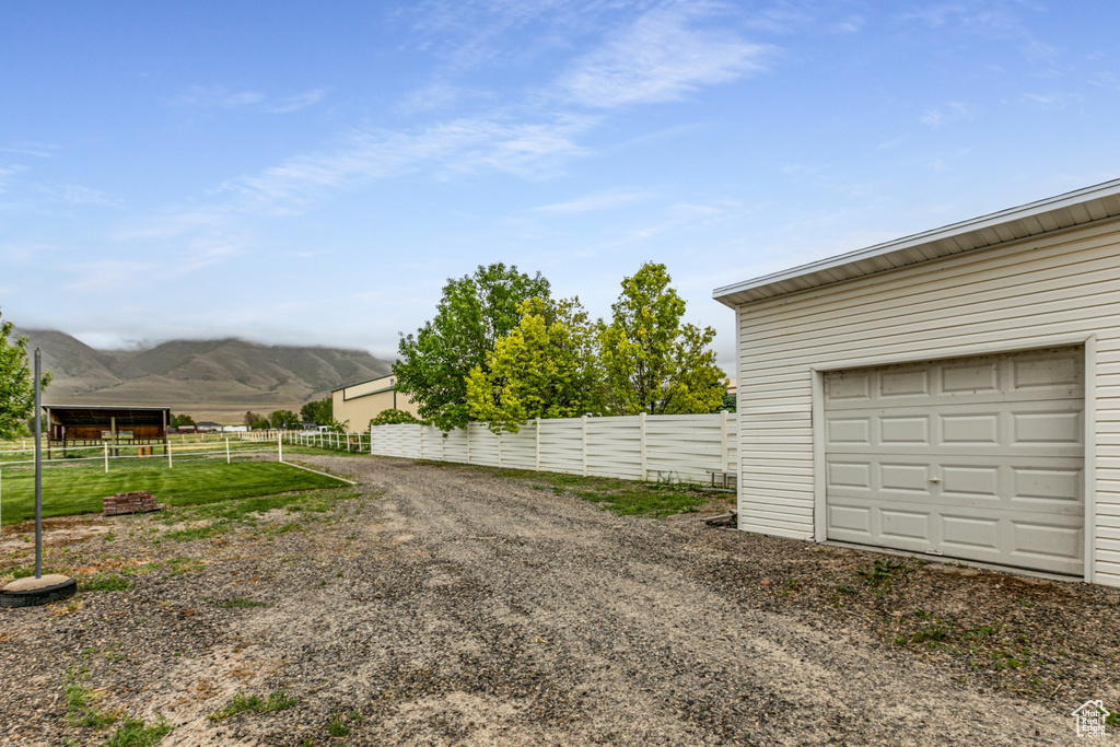 View of yard featuring fence, a mountain view, and a garage