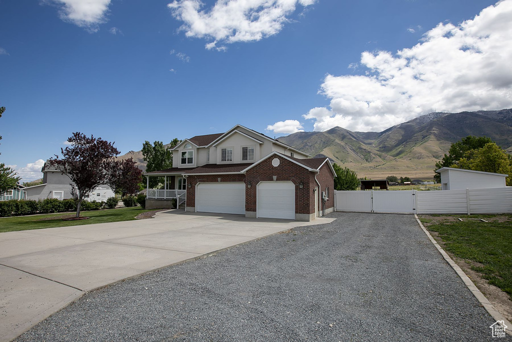 Traditional home featuring a gate, driveway, brick siding, fence, and a mountain view