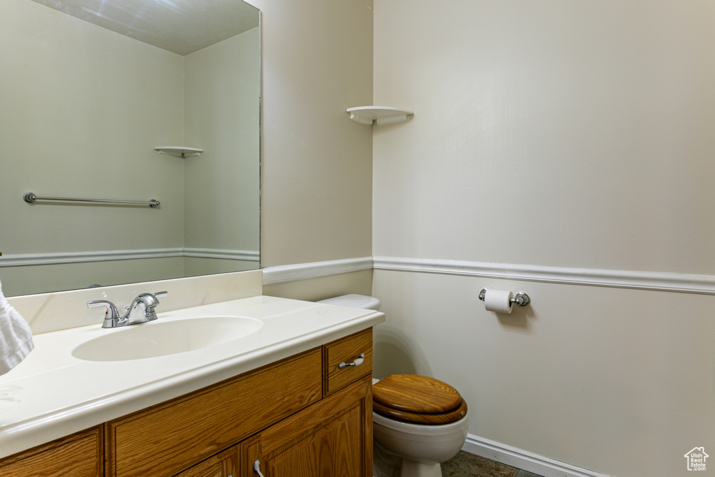 Half bath featuring toilet, vanity, and baseboards