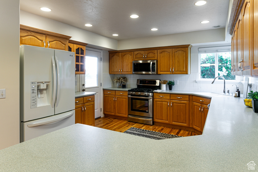 Kitchen with stainless steel appliances, a sink, plenty of natural light, brown cabinetry, and recessed lighting