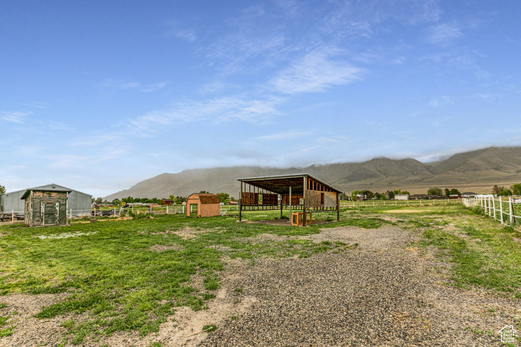 View of yard with a mountain view, an outbuilding, fence, a storage unit, and a rural view