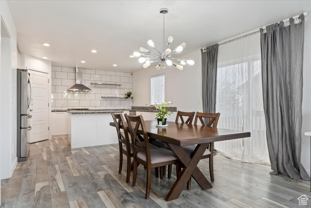 Dining space with a chandelier, light wood-style flooring, and recessed lighting